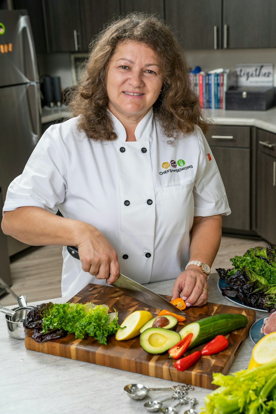 Chef smiles while chopping fresh vegetables for a healthy meal.