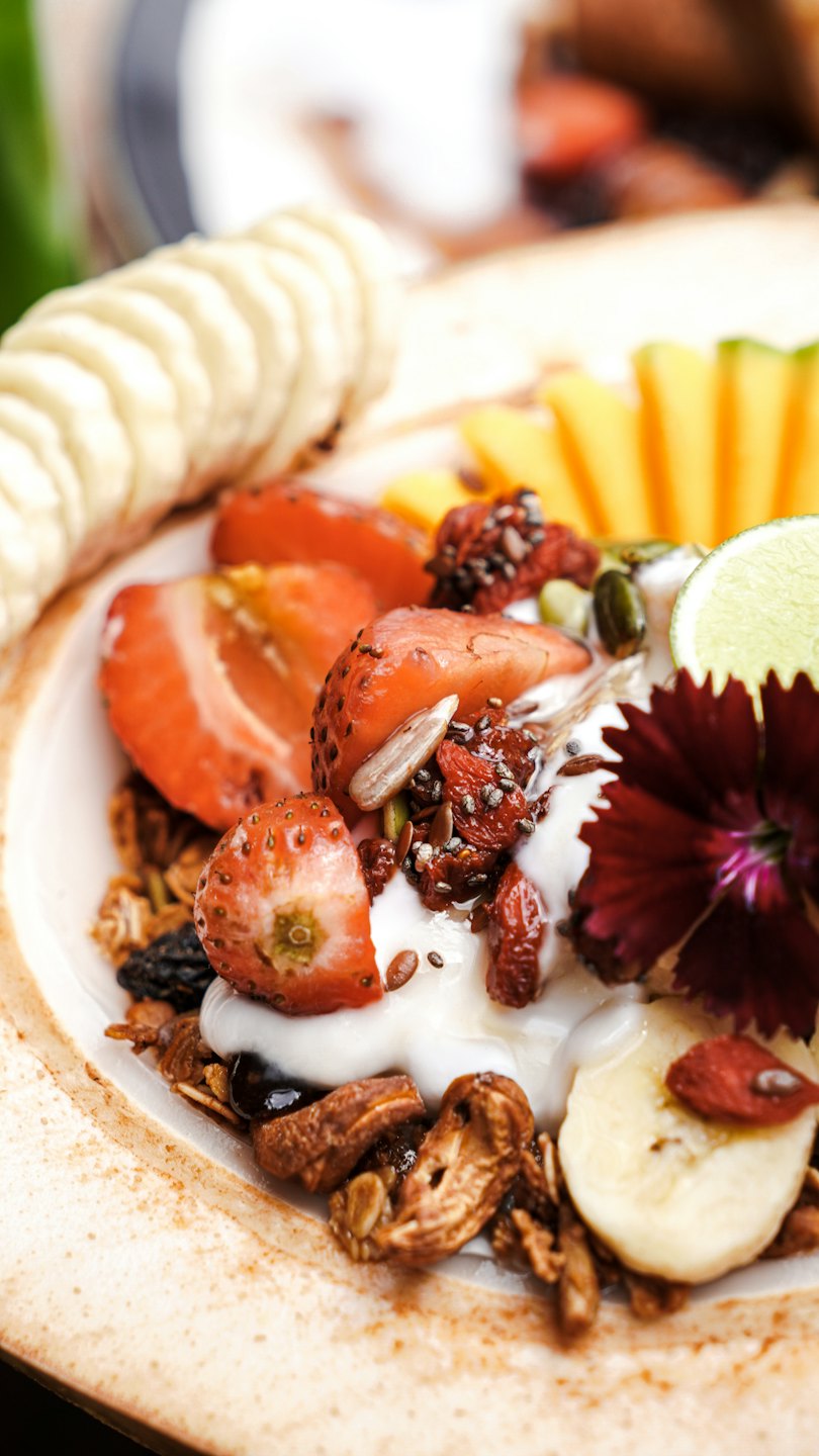 Granola bowl topped with fresh fruit and seeds in a rustic bowl.